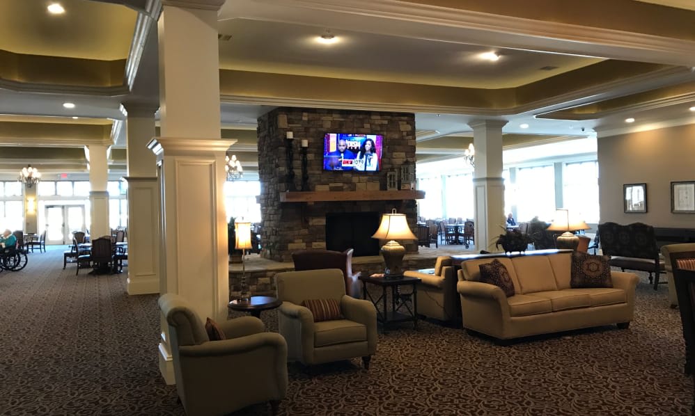 A cozy lobby seating area with sofas, armchairs, a fireplace, and a television.
