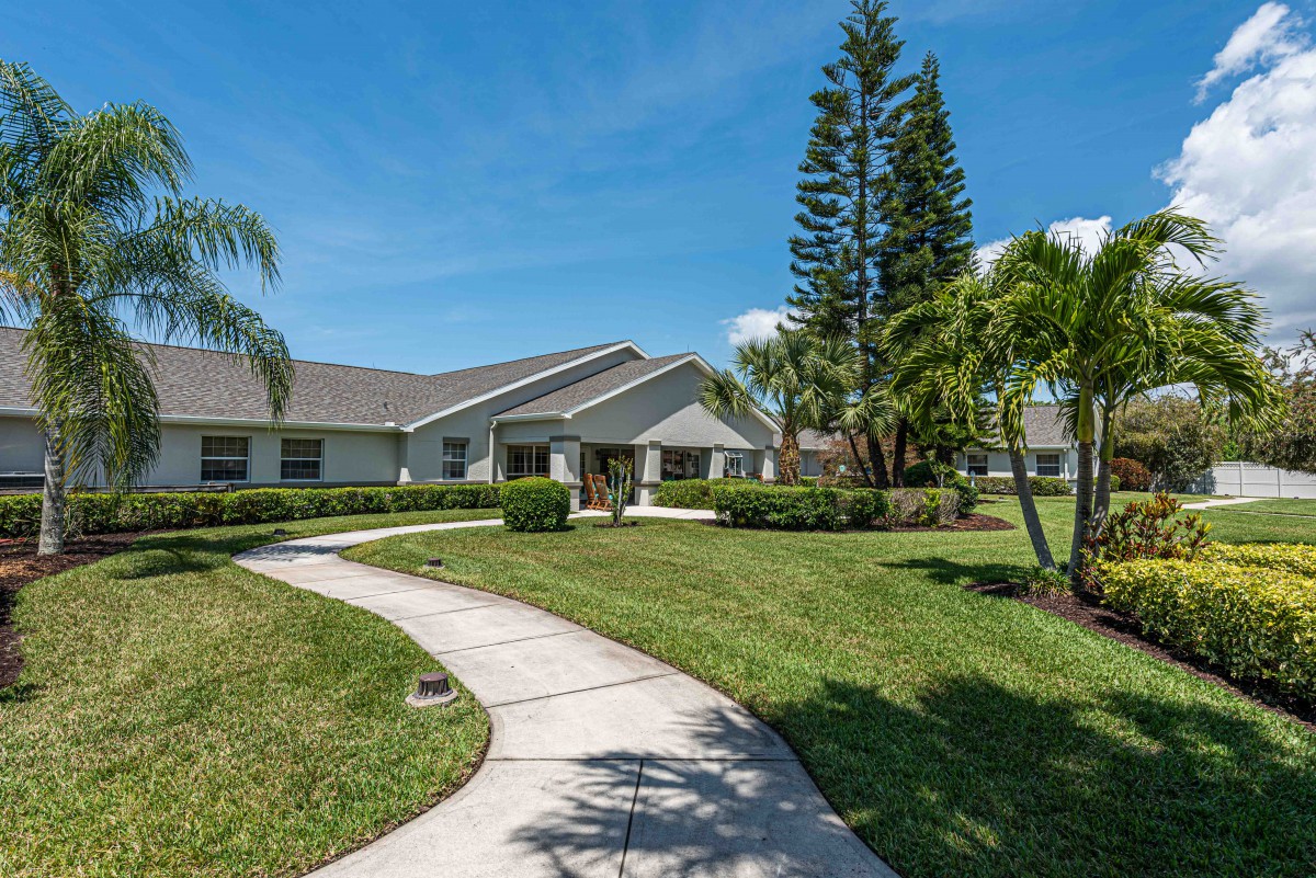 A residential house with a well-maintained lawn and pathway under a clear blue sky.