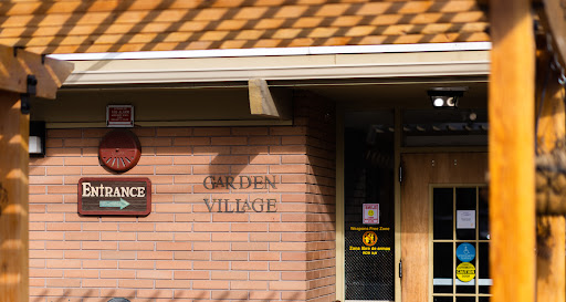 The entrance of Garden Village, featuring a prominent sign on a brick facade.