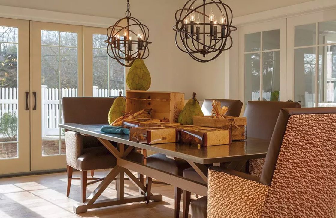A beautifully decorated dining room with a sunlit table and stylish chandeliers.