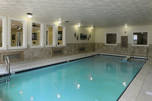 An indoor swimming pool with tiled walls and ceiling lighting.