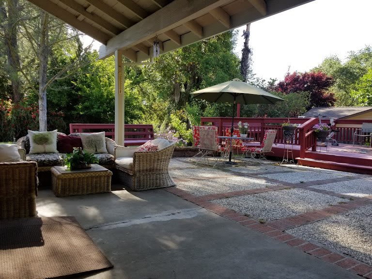 A cozy outdoor patio with comfortable seating and lush garden surroundings.