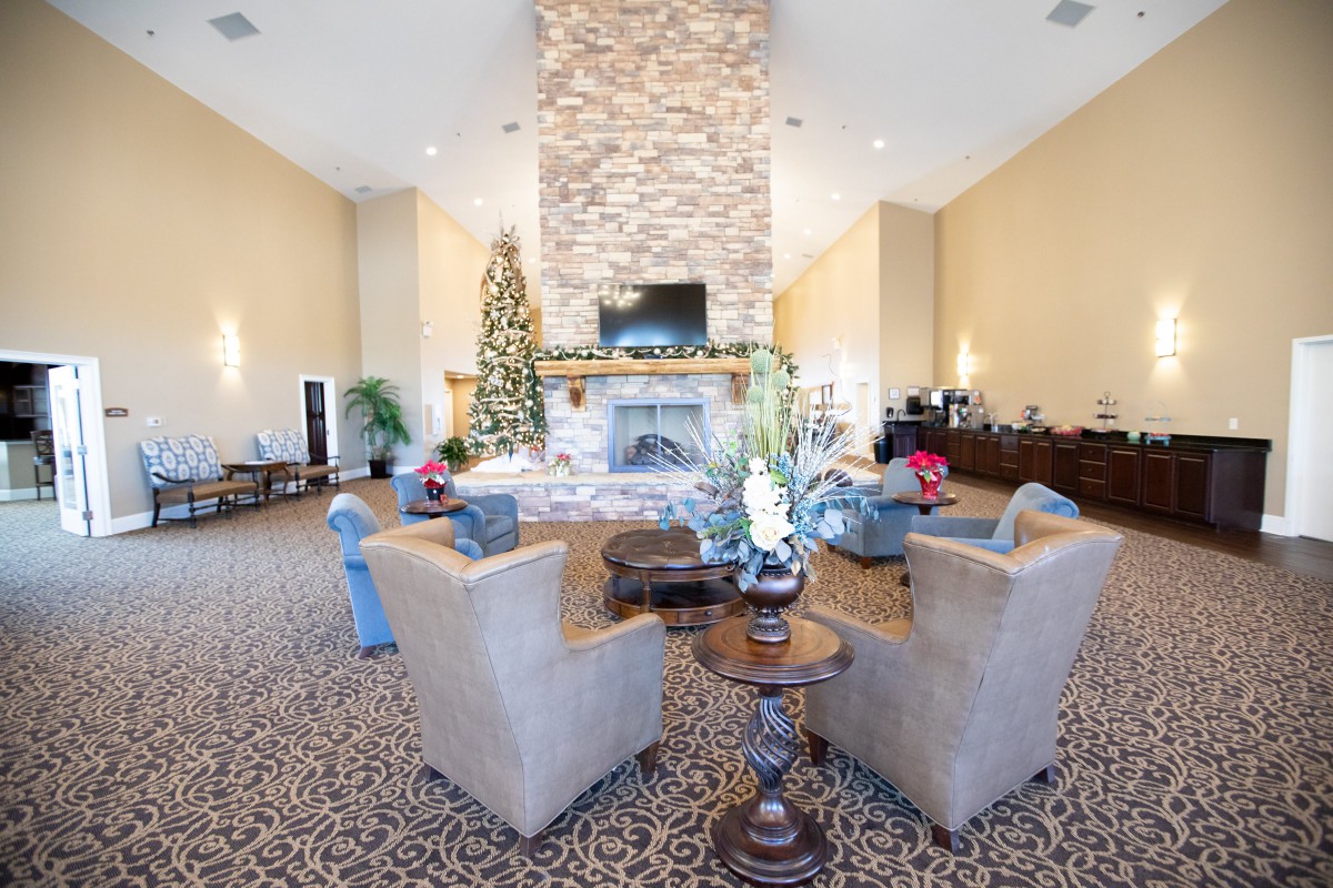 A spacious living room with a stone fireplace, comfortable seating, and holiday decorations.