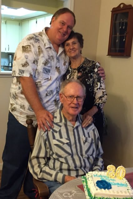 A group of three people posing together in a cozy indoor setting.