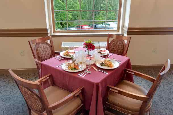 A beautifully set dining table for four, complete with plated meals and decorative centerpieces by a window.