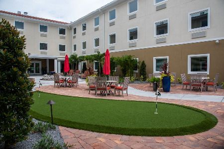 A hotel courtyard featuring outdoor seating with red umbrellas and well-maintained landscaping.
