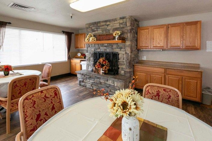 A cozy dining area featuring a stone fireplace and wooden cabinets, bathed in natural light.