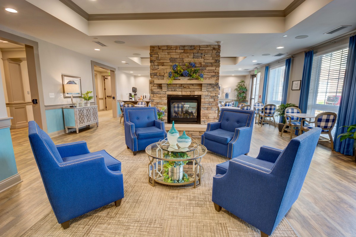 A modern living room with blue armchairs and a central fireplace.