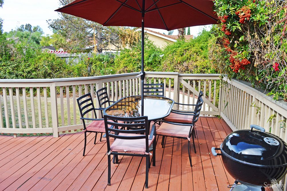An outdoor patio deck with a table, chairs, and an umbrella set up for relaxation.