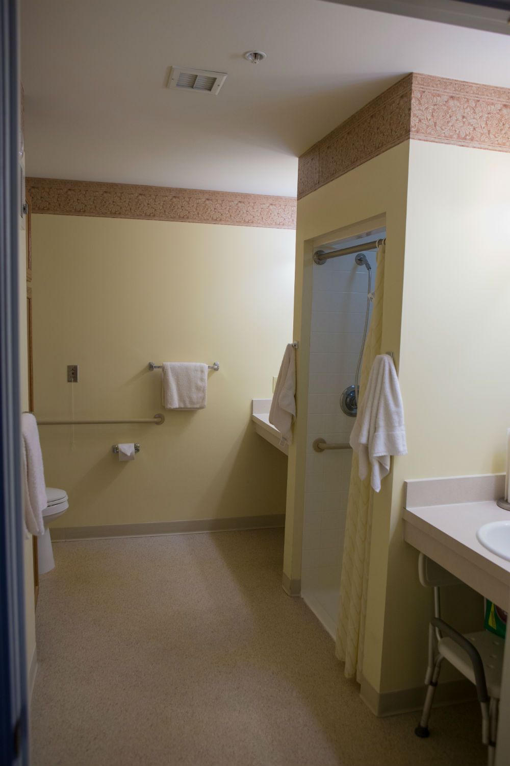 A clean, accessible bathroom with towels, a sink, and a shower.