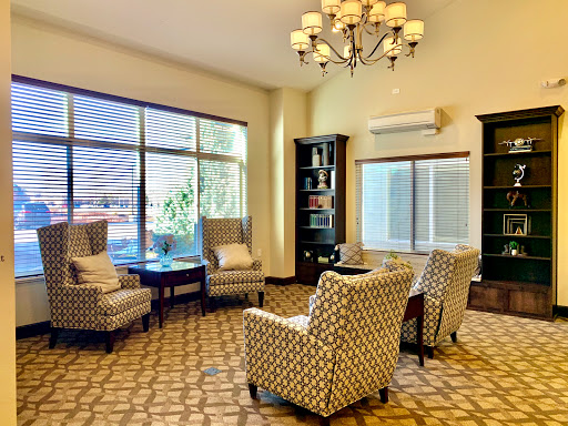 A cozy and inviting seating area with stylish chairs, a chandelier, and ample natural light.