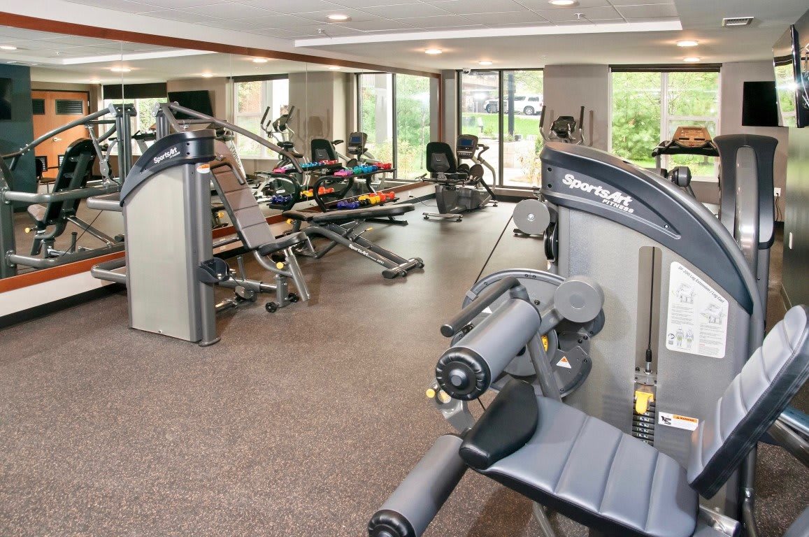 A well-equipped gym with various exercise machines and natural lighting.