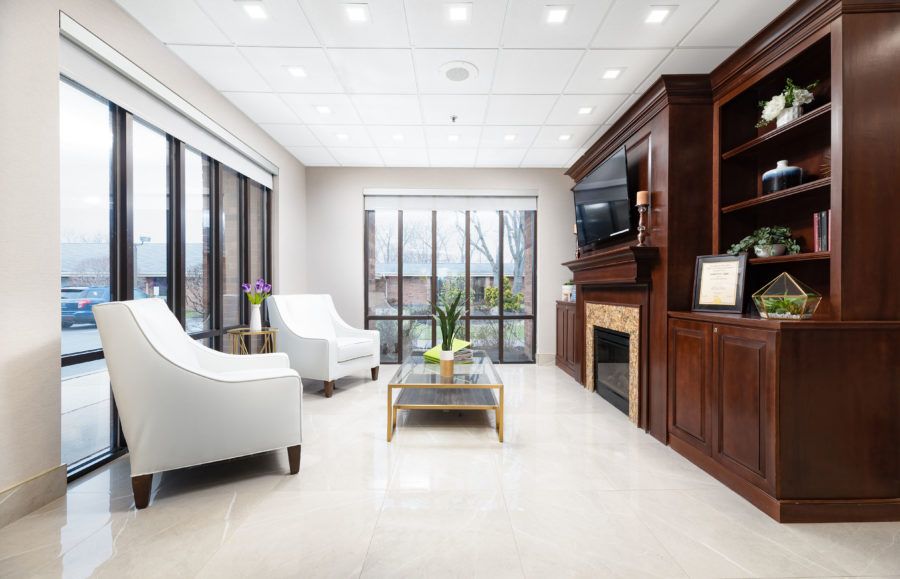 A modern living room with large windows, a fireplace, and elegant furniture.