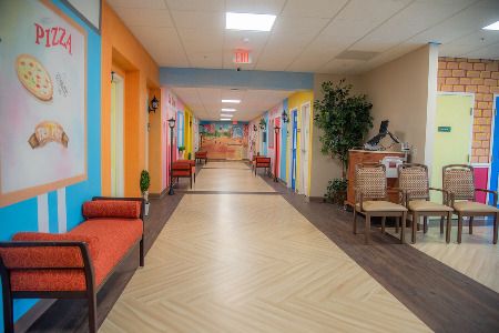 A vibrant and colorful hallway with seating areas and decorative indoor plants.