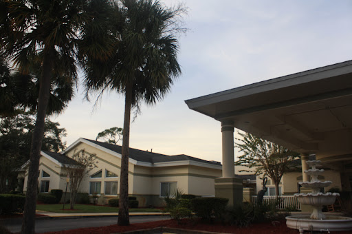 A view of a residential area featuring modern architecture and palm trees under a cloudy sky.