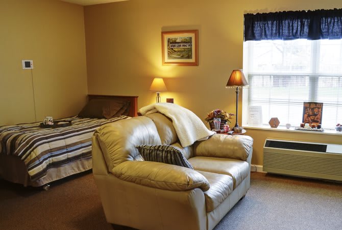 A cozy bedroom with a bed, sofa, and warm lighting.