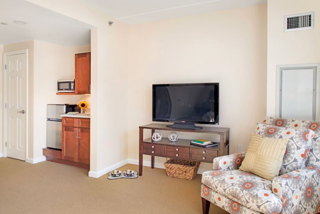 A cozy living room with a television and a glimpse into the kitchen area.
