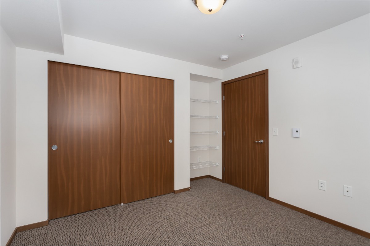 An empty room featuring wooden closets and built-in shelving.