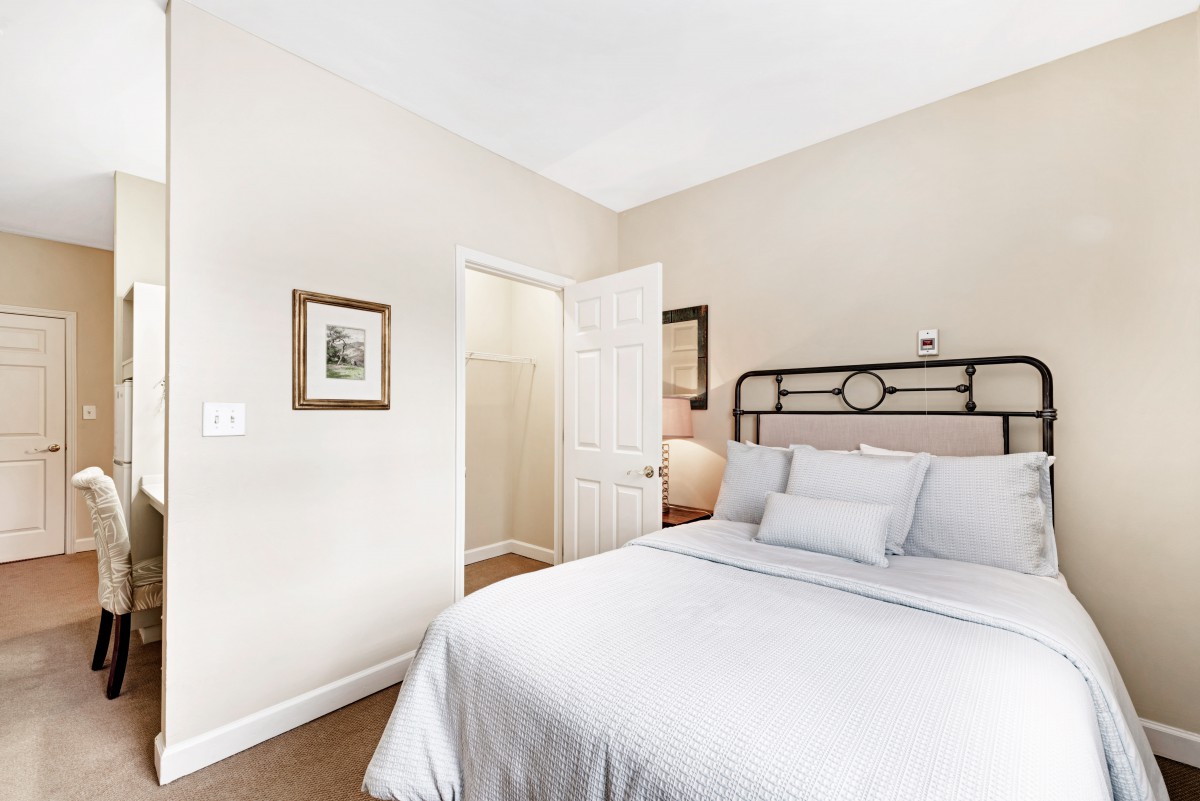 A minimalist bedroom with white bedding and simple decor.