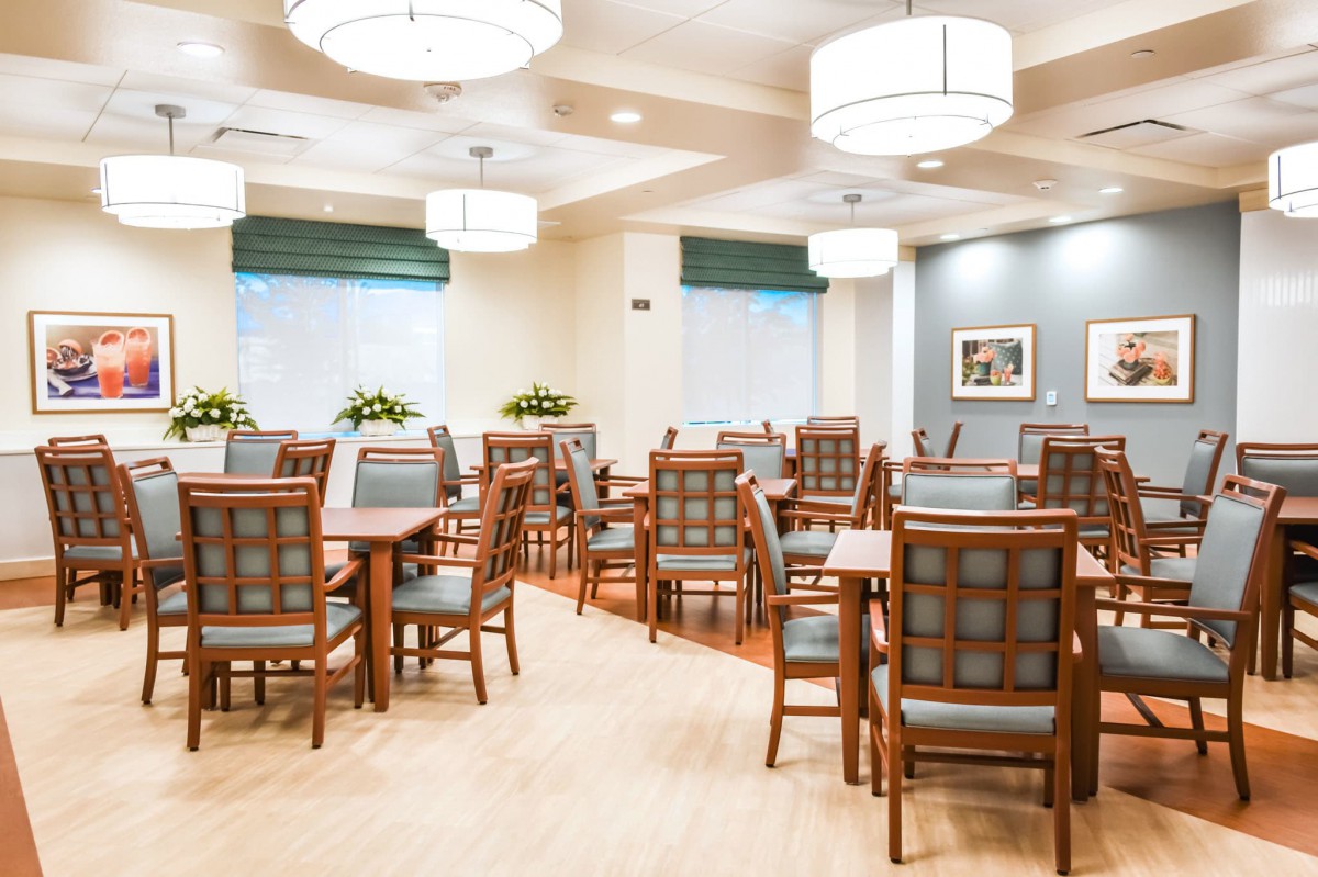 A spacious dining area with neatly arranged tables and chairs, featuring elegant lighting fixtures.