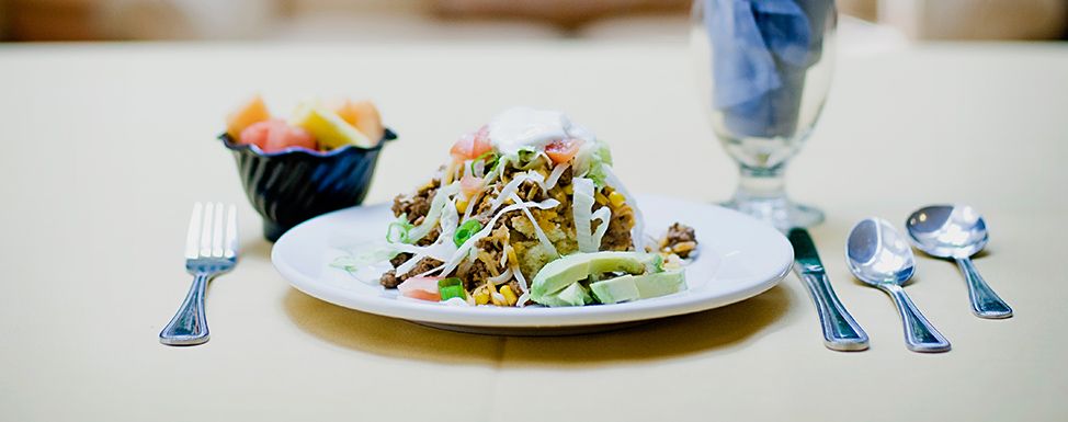A delicious taco salad topped with beef, fresh vegetables, and a dollop of sour cream.