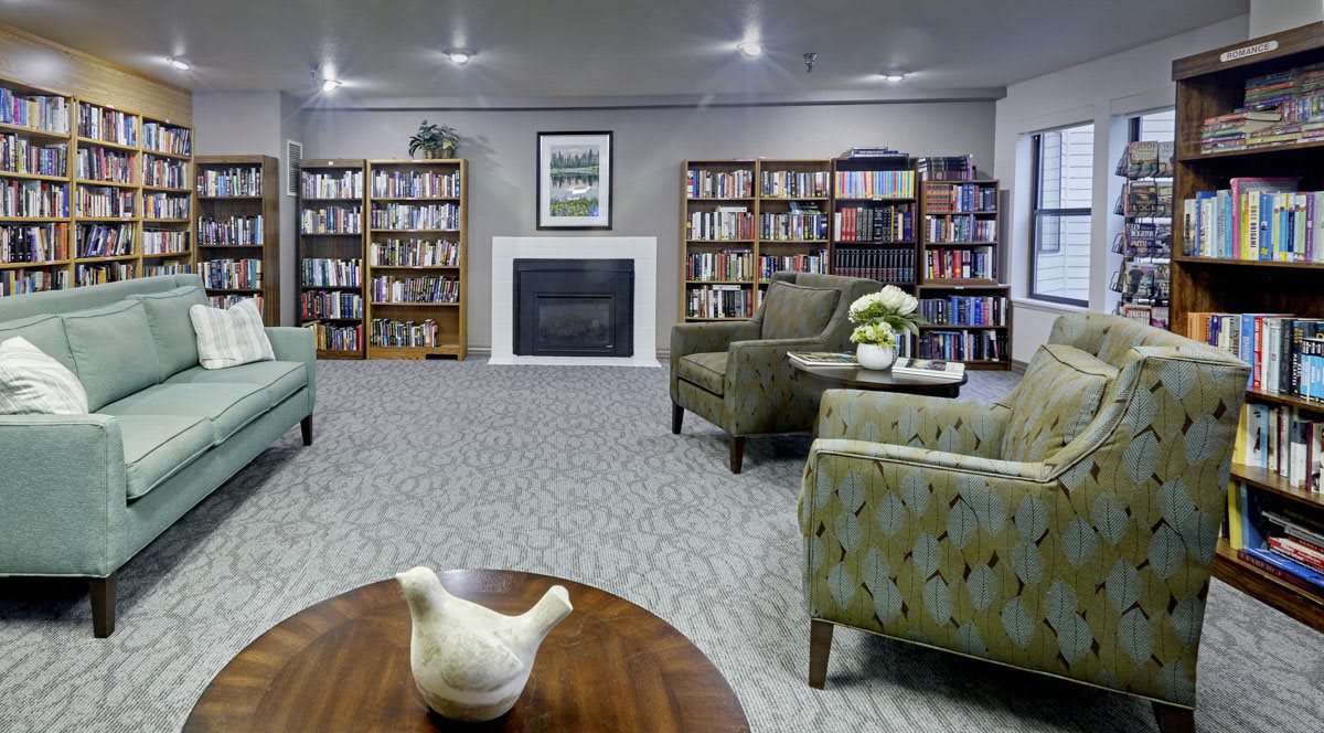 A cozy library with comfortable seating and a fireplace.