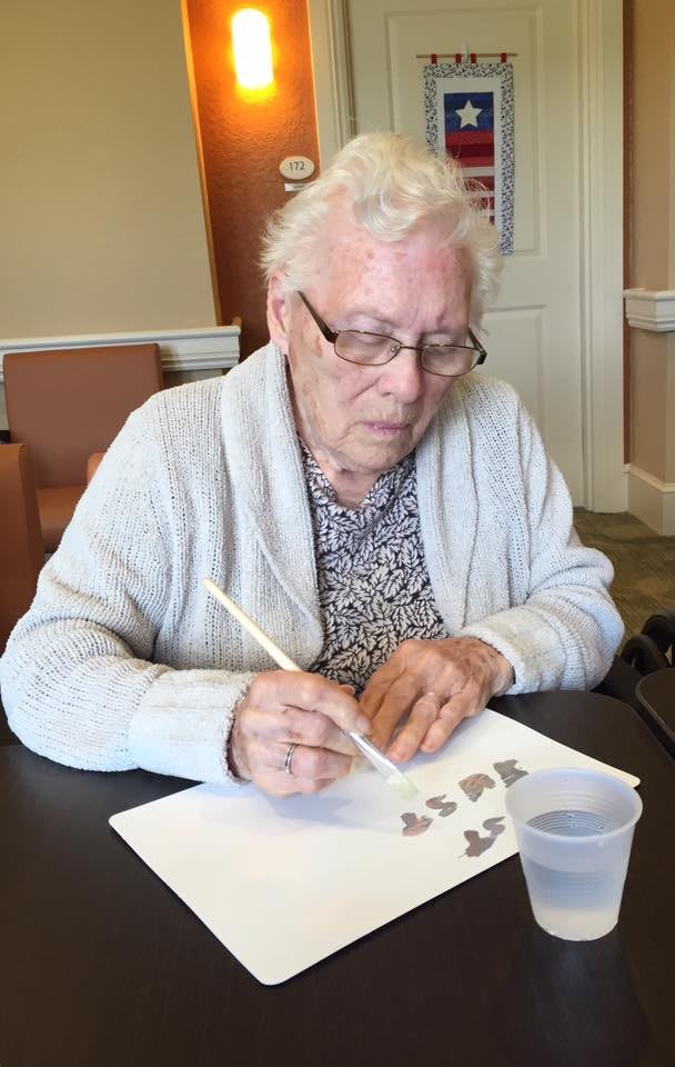 An elderly person engaged in painting indoors as a hobby.