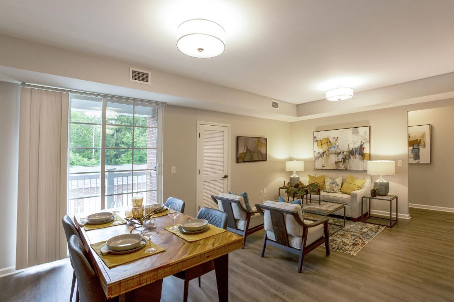 A modern and cozy living room with a connected dining area, featuring stylish furniture and warm lighting.