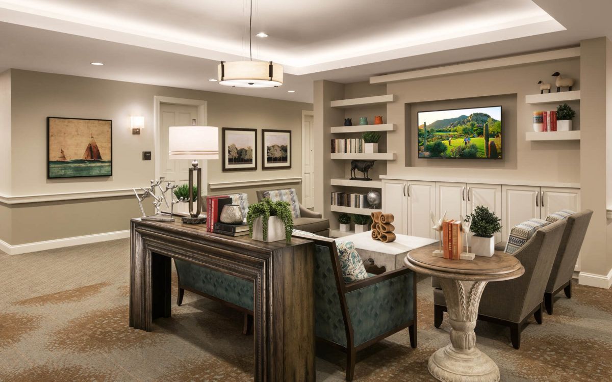 A modern living room with elegant decor, featuring a large wooden desk and comfortable seating, surrounded by shelves and framed artwork.