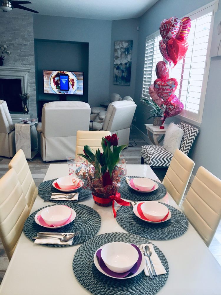 A beautifully set dining table with Valentine's Day decorations, including red roses and heart-shaped balloons in a cozy living room.