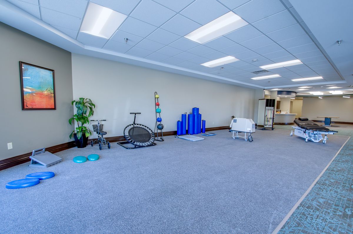 A spacious office area featuring exercise equipment and a modern design with carpeted floors and bright lighting.