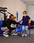 A therapist assists a young child using crutches during a physical therapy session.