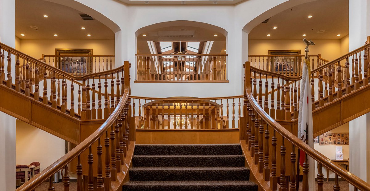 A luxurious interior with a grand wooden staircase and skylights.