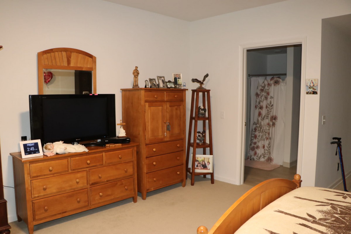 A cozy bedroom featuring wooden furniture, including a dresser with a mirror and a television on top.