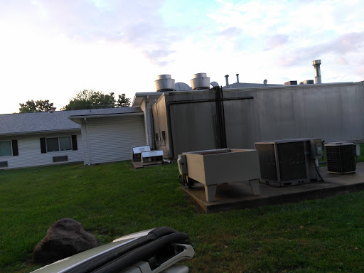 A view of a building's exterior featuring air conditioning units on the side lawn.