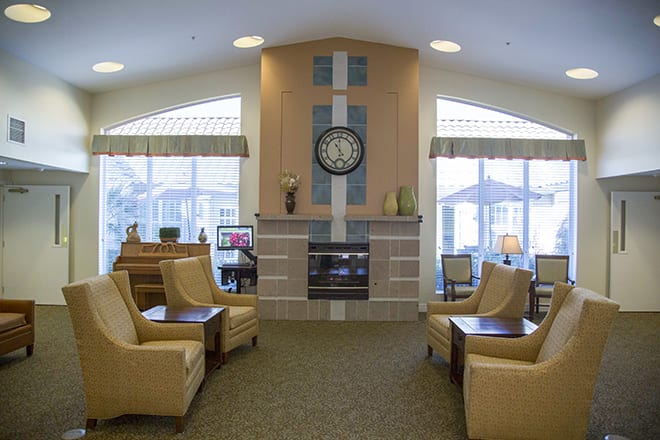 A cozy living room featuring a central fireplace, surrounded by comfortable seating and large windows.