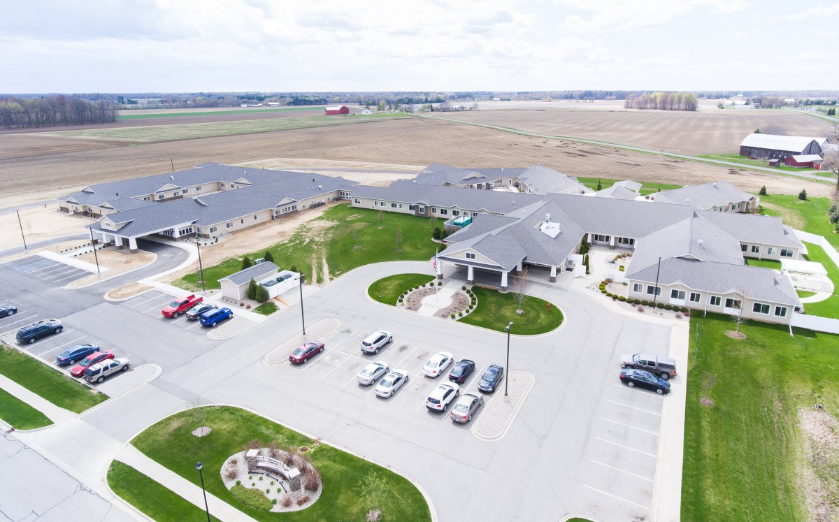 Aerial view of a building complex with a parking lot surrounded by open fields.