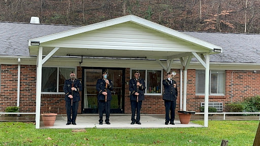 Members of the honor guard perform a salute in front of a building.