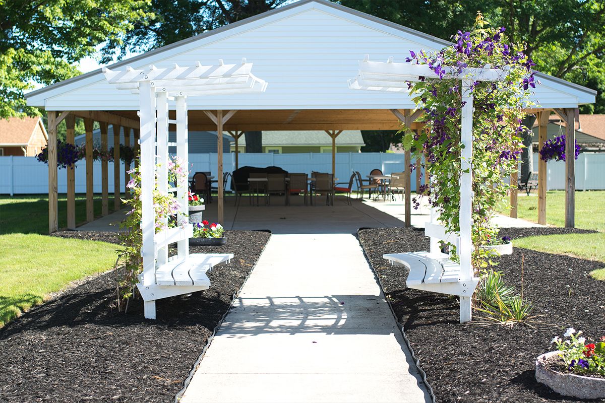 A beautifully landscaped garden area with a pergola and benches leading to a gazebo.