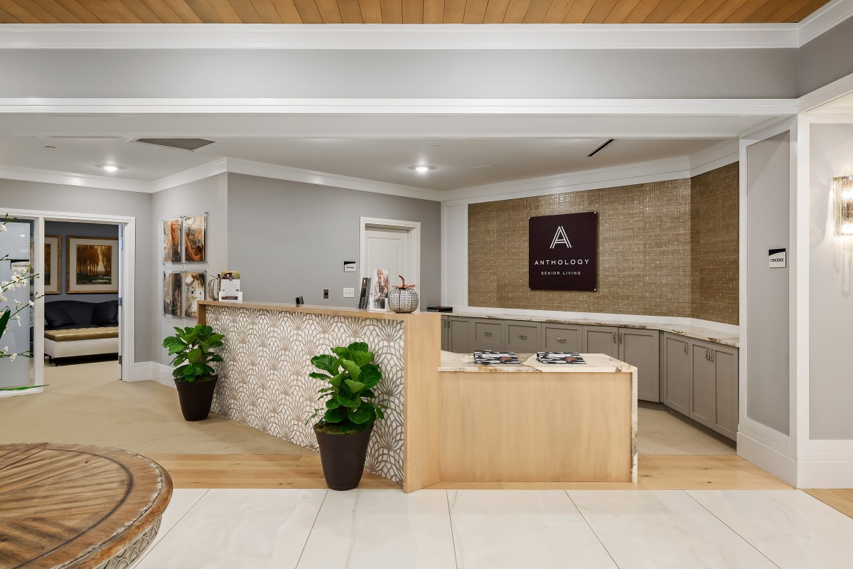 A modern reception area with a sleek front desk and decorative plants.