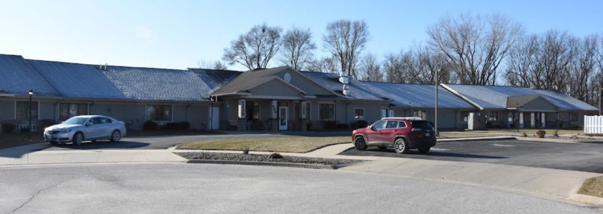 A suburban house with a red SUV parked in the driveway on a clear day.