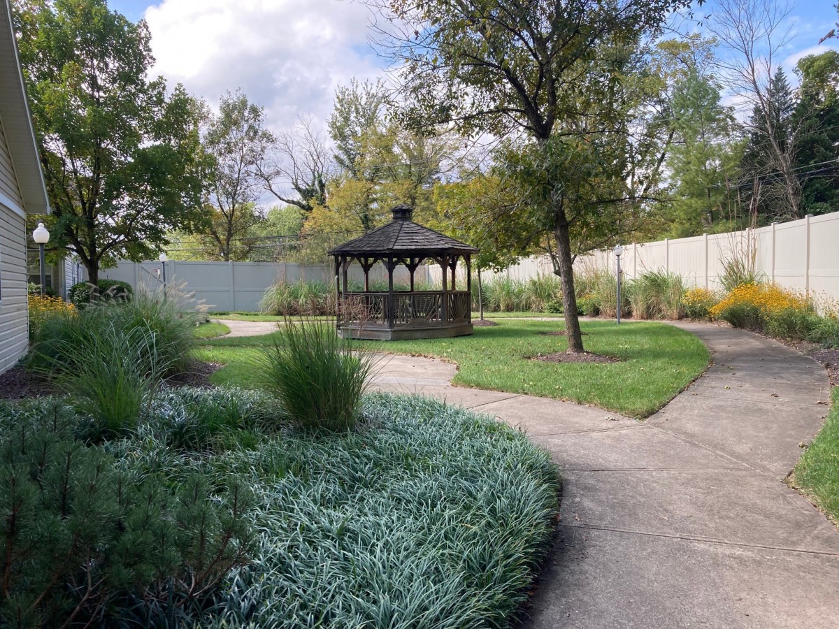 A serene garden with a central gazebo surrounded by lush greenery and winding pathways.