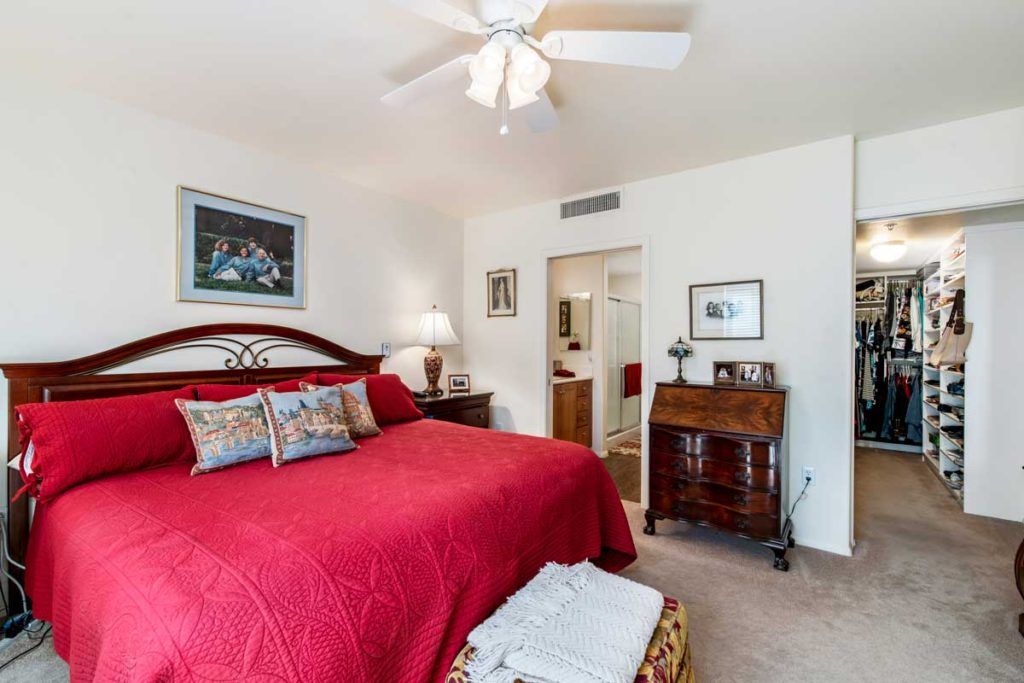A cozy bedroom with a red bedspread and elegant decor.