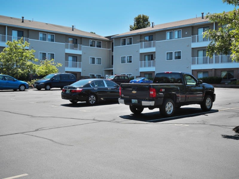 Cars parked in front of an apartment complex on a sunny day.