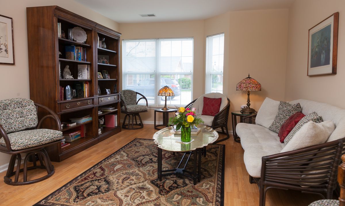 Cozy living room with a bookshelf, sofa, and coffee table adorned with flowers.
