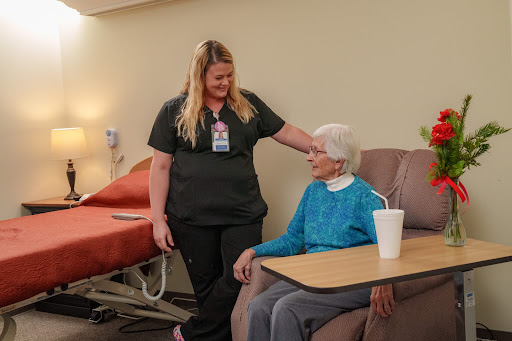 A caregiver interacts warmly with an elderly resident in a healthcare setting.