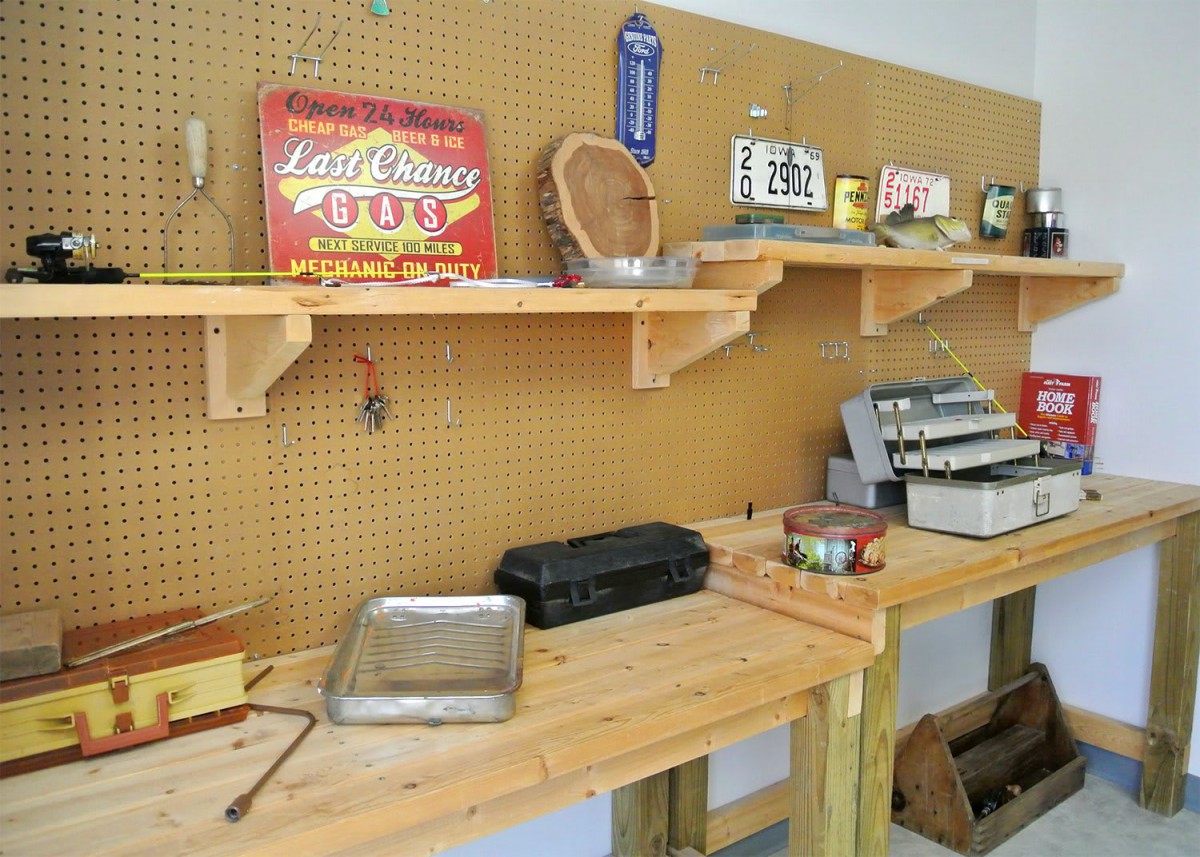 A well-organized workshop featuring tools and vintage signs displayed on a pegboard with wooden shelves.