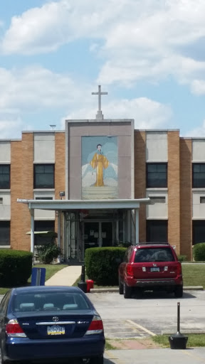 Front view of a church featuring a mural and a cross.