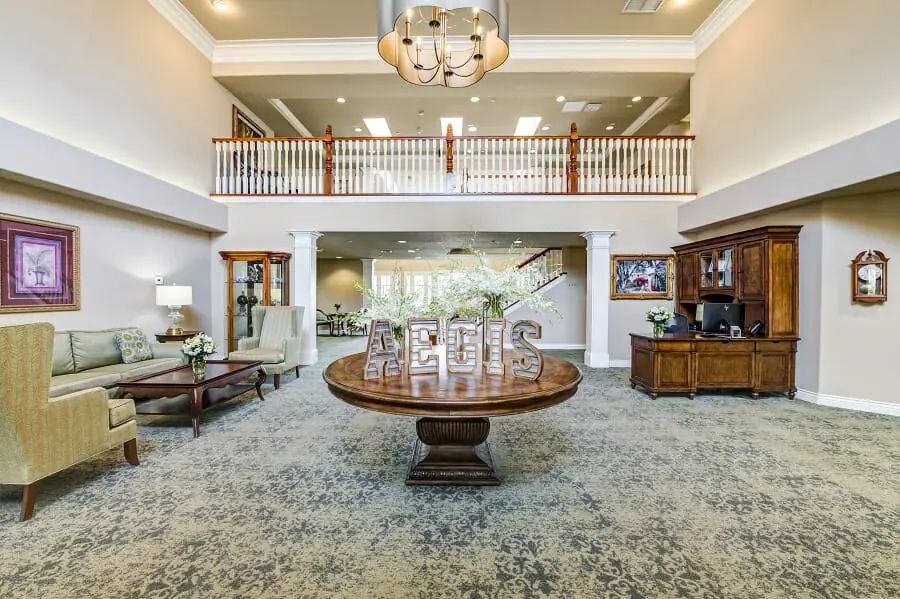 A luxurious lobby with elegant decor, featuring a central round table, chandelier, and stylish furnishings.