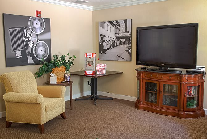 A cozy living room featuring a TV, popcorn machine, and comfortable seating.